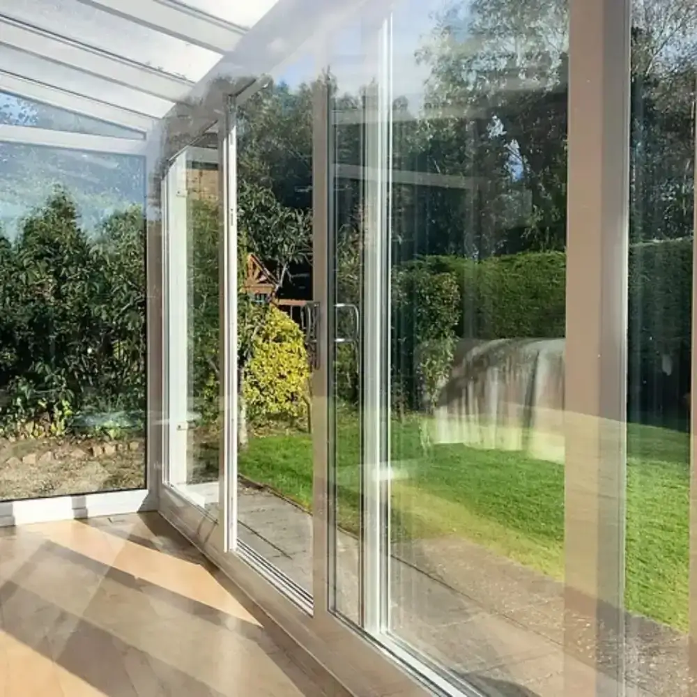 Bright glass conservatory with sliding doors offering a scenic garden view.